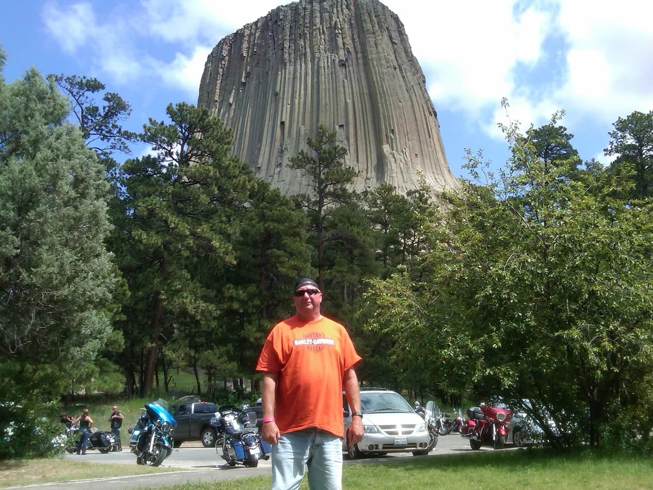 Michael Gunn at Devils Tower, bikes lined up along the road behind him