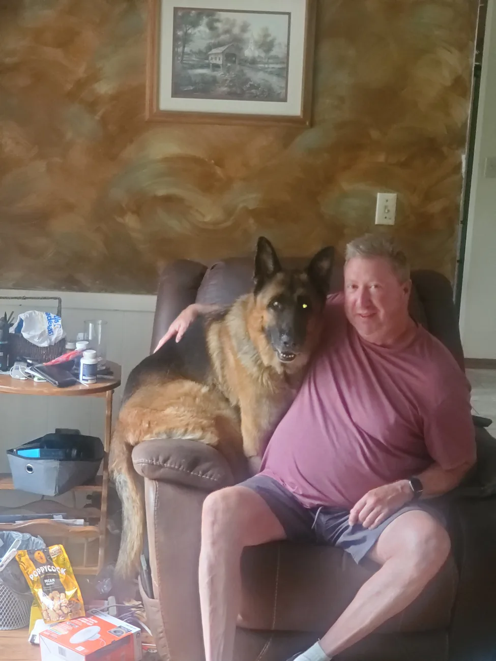 The German Shepherd leaning over the back of the recliner behind Michael